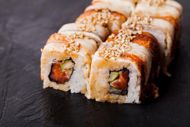 Primer plano de unagi sushi roll sobre un fondo de pizarra negra