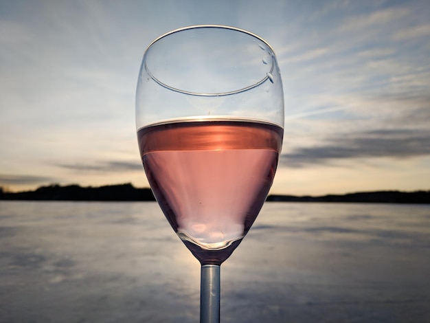 Primer plano de un vaso de agua contra el cielo durante la puesta de sol