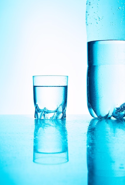 Primer plano de un vaso de agua en la mesa contra un fondo azul