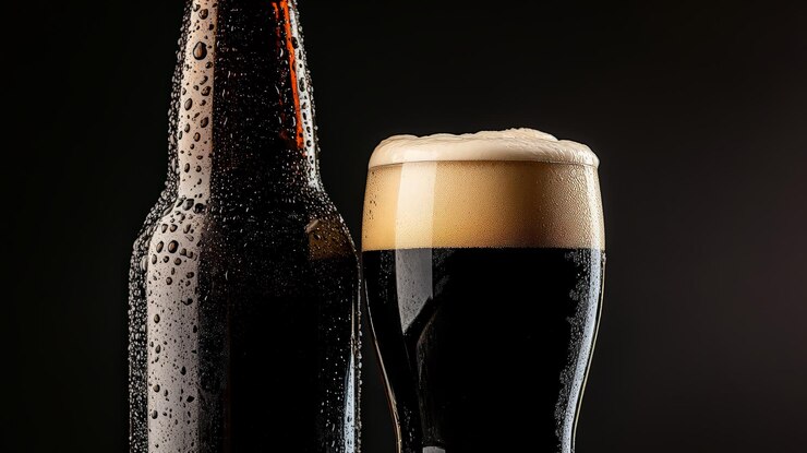 Primer plano de un vaso y una botella de cerveza oscura fría con condensación