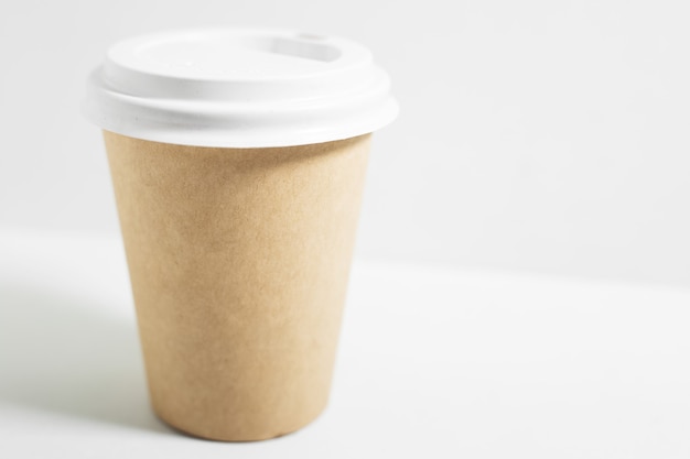 Primer plano de un vaso de papel desechable para llevar café, con tapa blanca, aislado en blanco.