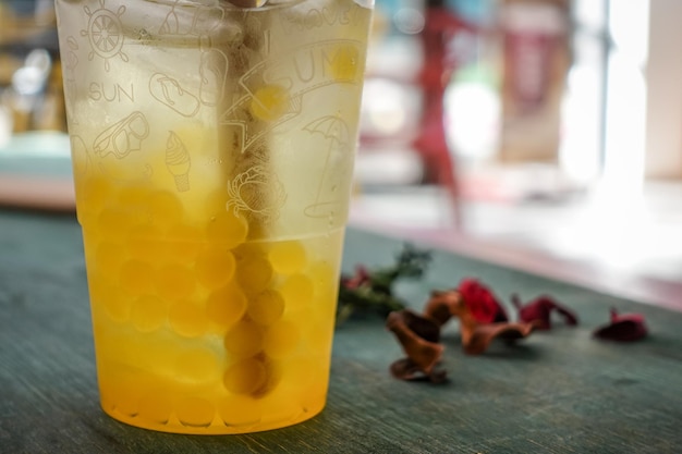 Primer plano de un vaso con té de burbujas con sabor a mango con hielo