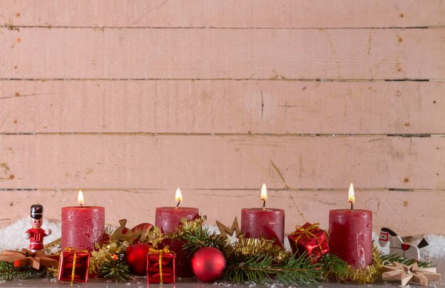 Primer plano de velas iluminadas con decoraciones navideñas en la mesa contra la pared