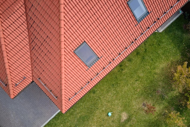 Primer plano de las ventanas del ático en la azotea de la casa cubierta con tejas de cerámica Revestimiento de azulejos del edificio