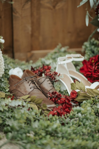 Primer plano vertical de los zapatos de la novia y el novio aislados en las plantas y flores