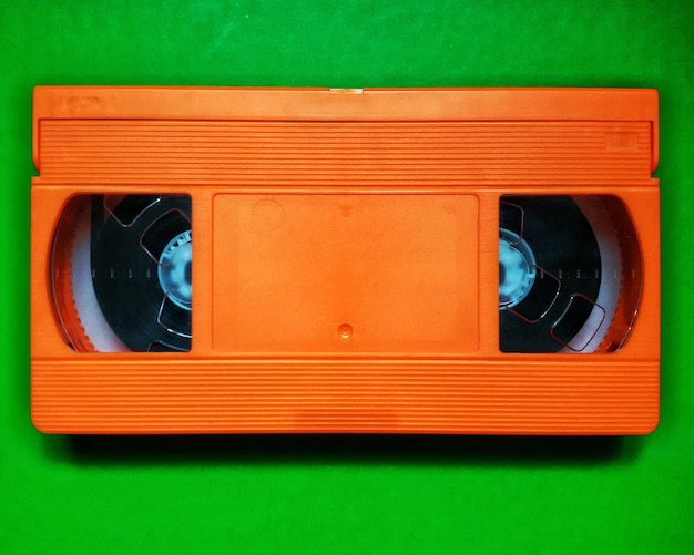 Foto primer plano de una videocasseta naranja en una mesa verde