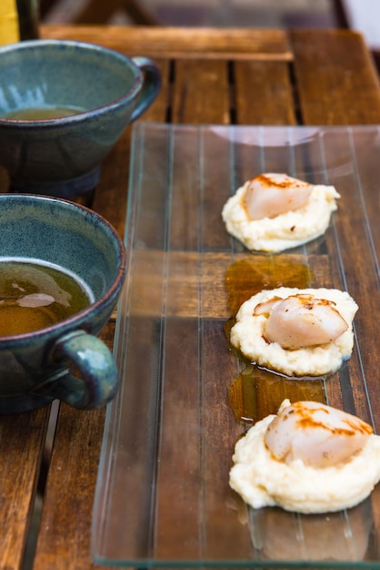 Primer plano de vieiras a la plancha y una taza de sidra