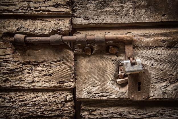 Primer plano de una vieja cerradura de hierro en una puerta antigua de madera, fondo rústico grunge