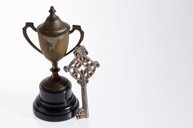 Primer plano de un viejo trofeo y una llave antigua sobre un fondo blanco