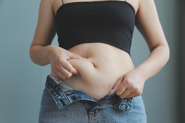 Primer plano de un vientre con cicatriz de cesárea y grasa abdominal Salud de la mujer Una mujer vestida con ropa deportiva que demuestra su cuerpo imperfecto después de un parto con guardería en el fondo