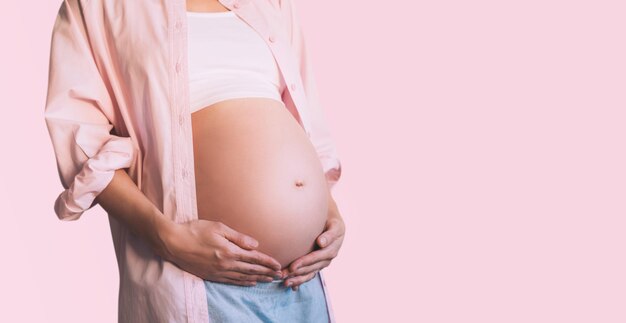 Primer plano del vientre de una hermosa mujer embarazada con sus manos Madre feliz esperando el nacimiento del bebé Preparación y expectativa de la maternidad del embarazo