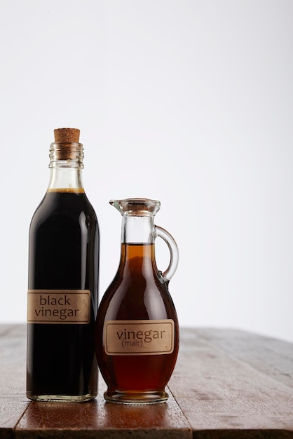 Primer plano de vinagre en botellas en la mesa contra un fondo blanco