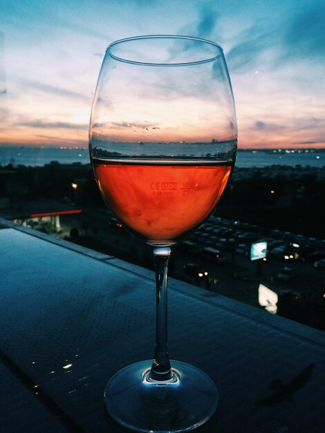 Foto primer plano de vino en vaso en la mesa contra el cielo durante la puesta de sol