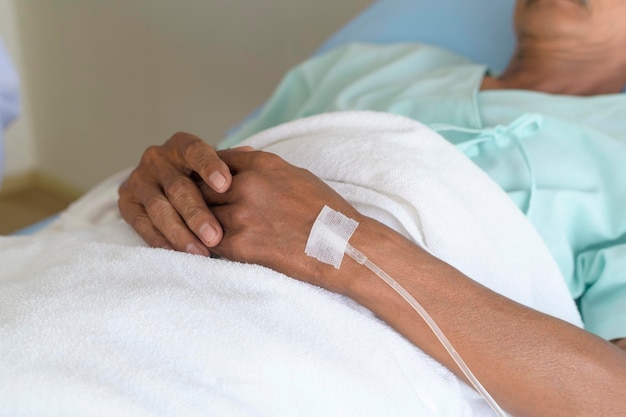 Foto primer plano del visitante que sostiene la mano de los pacientes mayores en el concepto médico y de atención médica del hospital