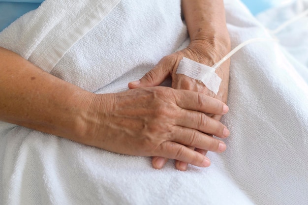 Primer plano del visitante que sostiene la mano de los pacientes mayores en el concepto médico y de atención médica del hospital