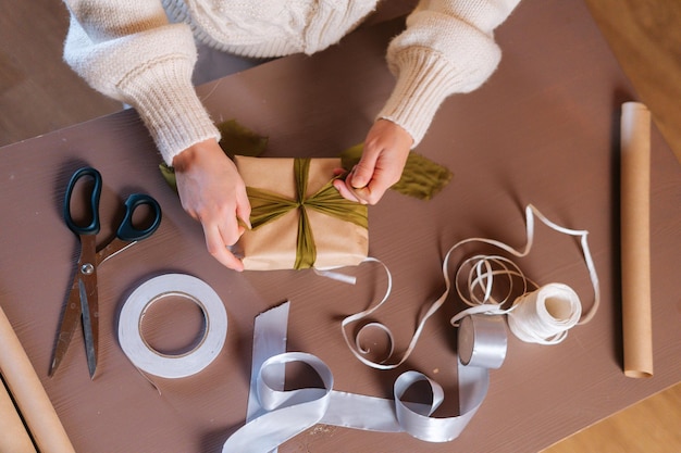 Primer plano vista highangle de irreconocible joven atar cinta en caja de regalo de navidad envuelto con