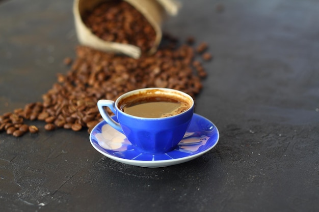 Primer plano y vista superior de café negro caliente en taza de café azul y granos de café tailandés tostados en madera