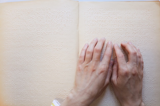 Primer plano de vista superior de ciego irreconocible leyendo espacio de copia de libro en braille