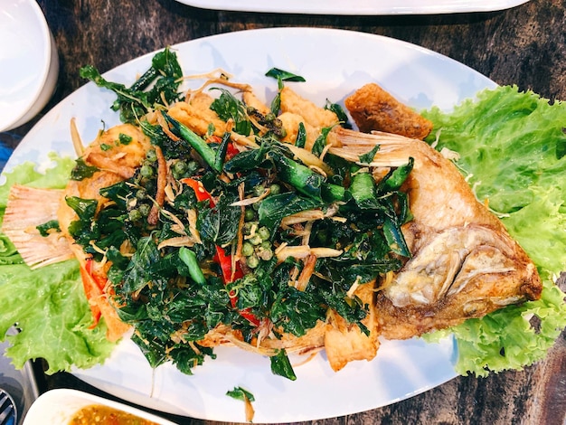 Primer plano y vista superior Tilapia frita con hierbas en un plato de cerámica blanca Comida tailandesa popular