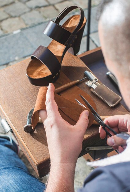 Foto primer plano de un zapatero haciendo sandalias en el taller