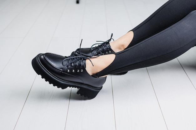 Primer plano de zapatos con cordones de cuero negro en piernas femeninas en polainas negras Zapatos de otoño con estilo de mujer