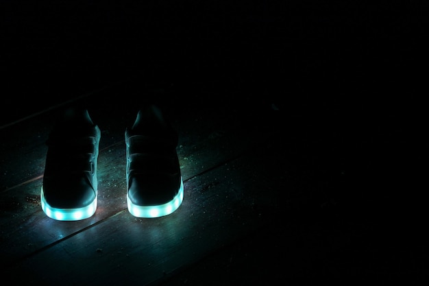 Primer plano de zapatos iluminados en el cuarto oscuro