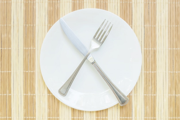 Primer plato de cerámica con tenedor y cuchillo de acero inoxidable en medio de comer sin terminar