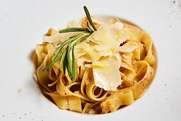 Primer plato de pasta italiana con queso parmesano rallado y hojas de albahaca