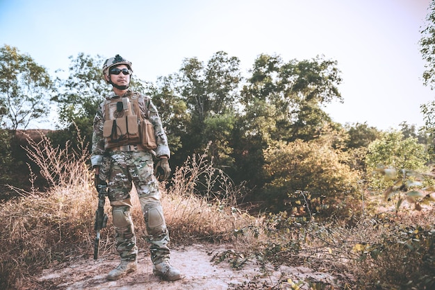 Primer soldado asiático con armas en la mano en el bosqueprepárate para el concepto de veteranos de maniobra militar