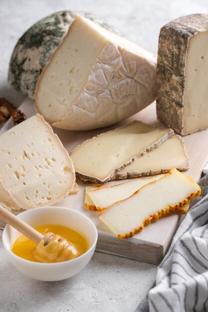 Primer surtido de lonchas de quesos blandos sobre tabla de madera. Queso Cornish Yarg de cabra de granja