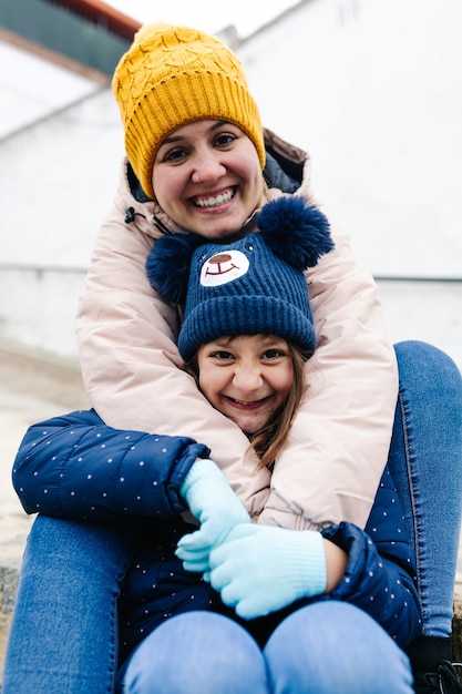 Primer tiro de feliz madre e hija sentadas en las escaleras