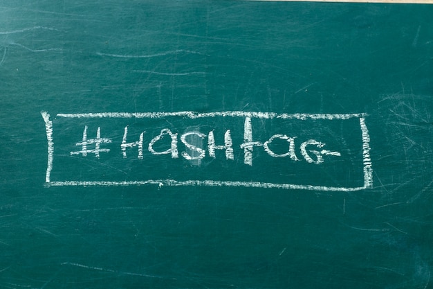 Primer en la tiza blanca del símbolo del hashtag en un espacio verde de la copia de la pizarra