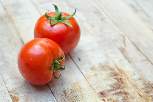 Primer de tomates frescos, maduros en el fondo de madera.