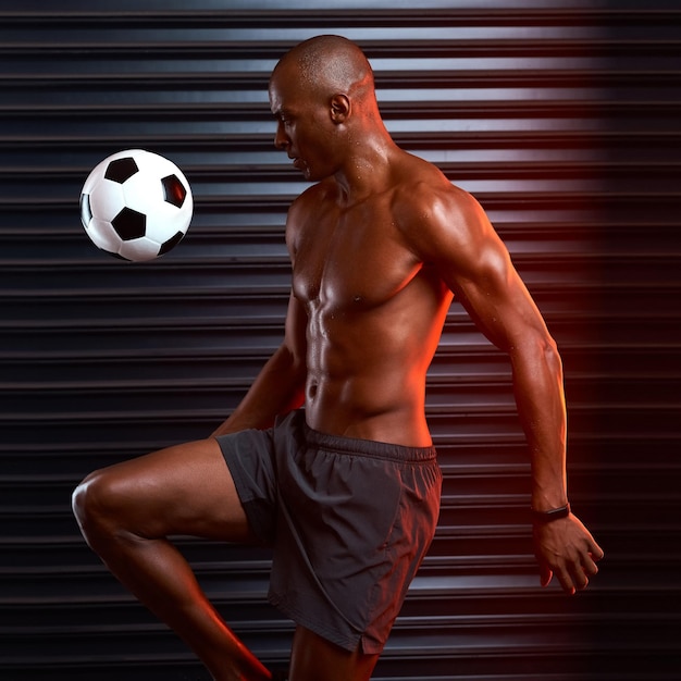 Primer toque perfecto Foto de estudio de un joven atlético jugando con una pelota de fútbol contra un fondo gris