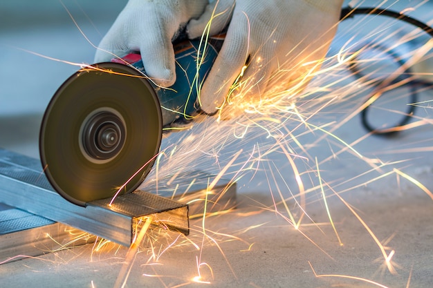 Primer del trabajador que corta el metal con la amoladora. Chispas al moler hierro.