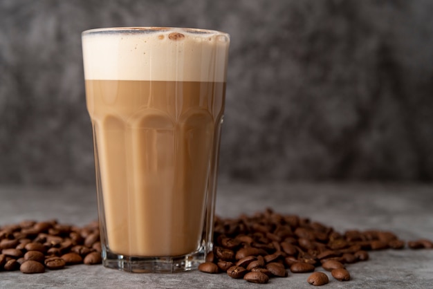 Foto primer vaso de capuchino con granos de café