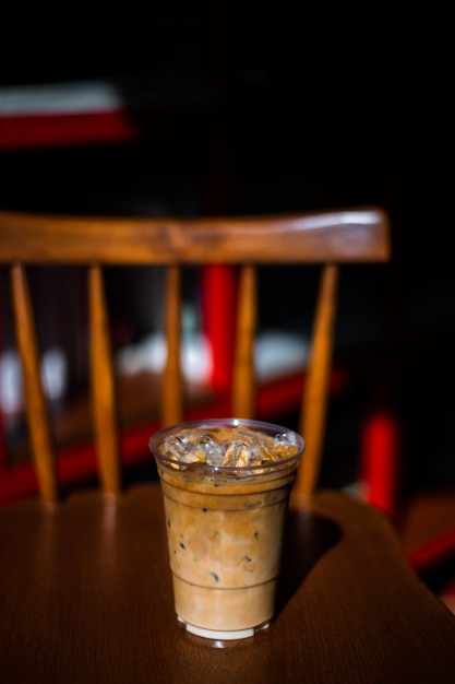 Primer vaso de plástico de café helado con leche sobre la mesa