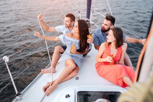 Primera pareja sentada en la proa del yate y mirar el atardecer