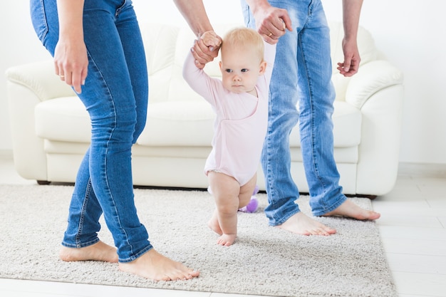 Primeros pasos. Niña aprendiendo a caminar. Sesión de estudio sobre fondo blanco.