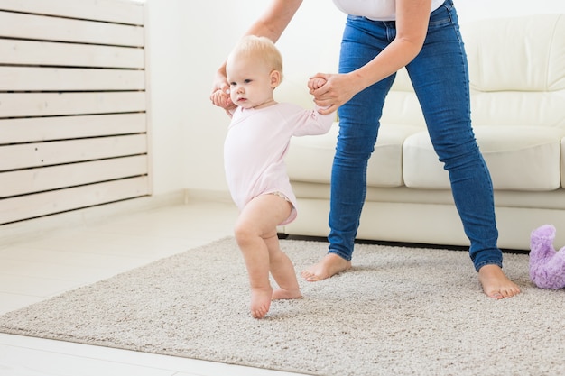 Primeros pasos de niña pequeña con la ayuda de mamá