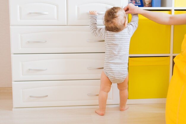 Primeros pasos del niño pequeño con la ayuda de la madre