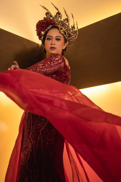 Princesa con un vestido rojo con la corona dorada en la cabeza frente a la iluminación