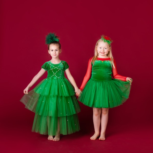 Princesas bonitas da menina que dançam no vestido verde luxuoso isolado na parede vermelha. Festa de Carnaval com fantasias