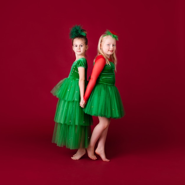 Princesas bonitas da menina que dançam no vestido verde luxuoso isolado na parede vermelha. festa de carnaval com fantasias