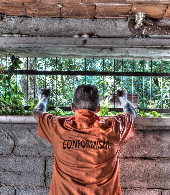 Prisioneiro de conformismo segurando barras de calabouço