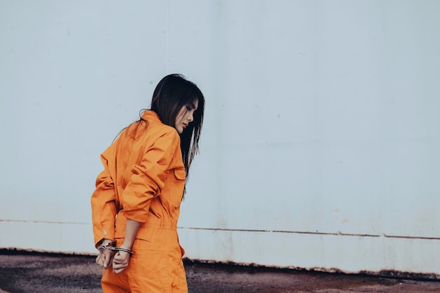 Prisioneiro no conceito de manto laranjaRetrato de mulher asiática em uniformes de prisão em fundo branco