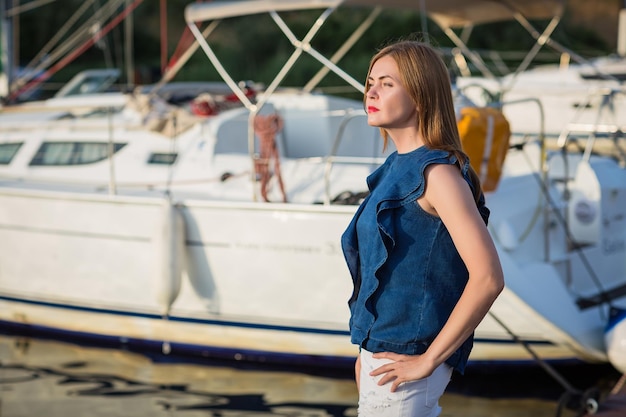 Foto pritty mujer posando en el puerto deportivo en un día soleado de verano en el río y disfrutando de felices fiestas