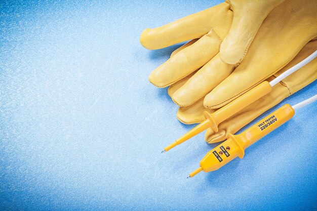 Foto probador eléctrico de guantes de seguridad sobre el concepto de electricidad de fondo azul.