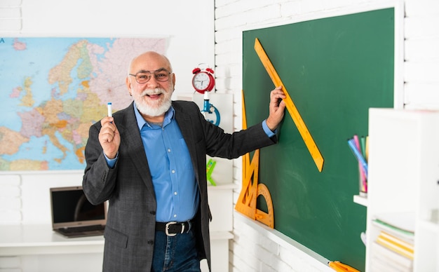 Probieren Sie aus, aus welchem Winkel Sie aussehen. Geometrische Formen High School Moderne Bildung Senior Lehrer verwenden Lineal beim Zeichnen Tutor Mann mit Brille zeichnen mit Lineal auf der Tafel zurück zur Schule