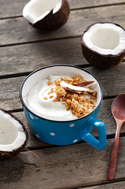 Probiotisches Lebensmittelkonzept. Bio-Kokosjoghurt mit Müsli in der Tasse auf rustikalem Holztisch